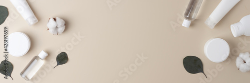 Cosmetic background with skin care products and flowers on pastel beige. Flat lay, copy space photo