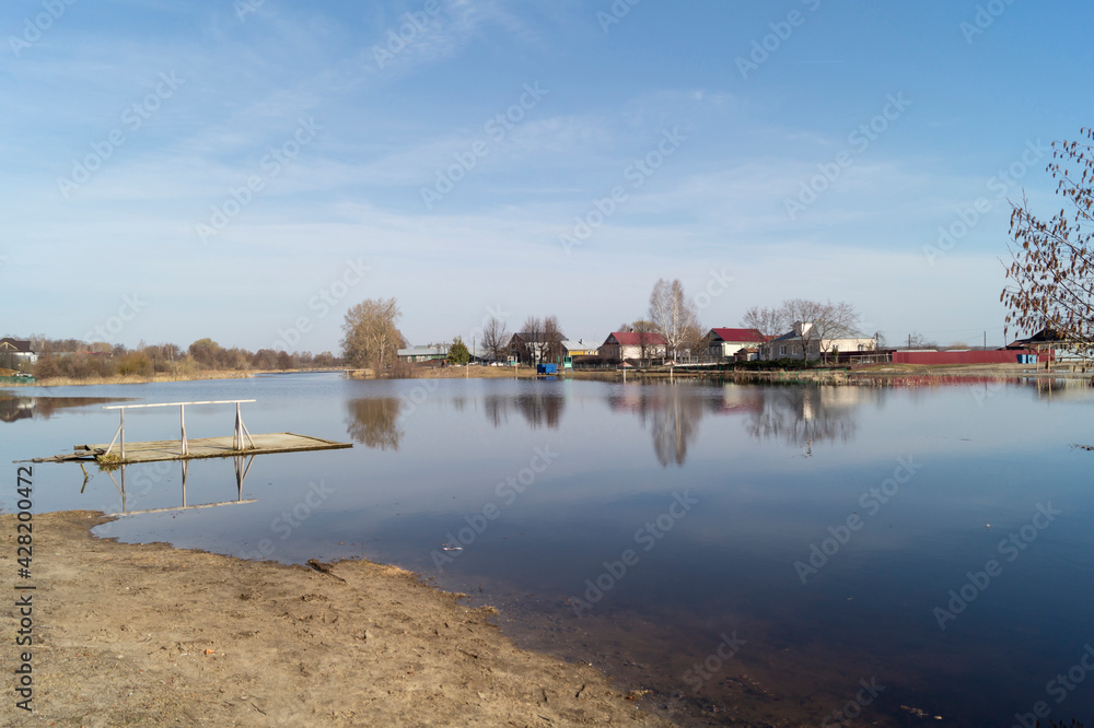 Spring flood in rural terrain on background blue sky with white cloud