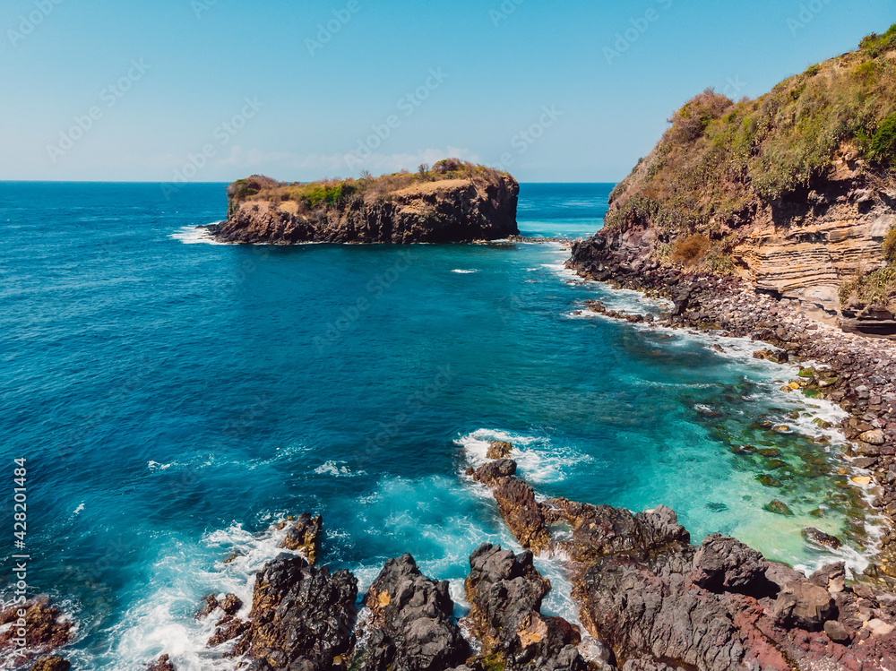 Fototapeta premium Blue transparent ocean with coastline and island. Aerial view.