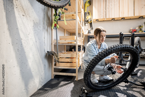 Young handywoman reparing her bicycle in the beautiful small workshop at home. DIY concept