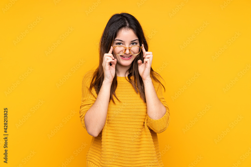 Young caucasian woman isolated on yellow background with glasses and surprised Young caucasian woman isolated on yellow background with glasses and surprised