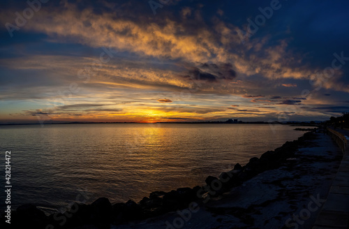 A sunset on the seashore. Soft sea ocean waves wash over golden sand background.