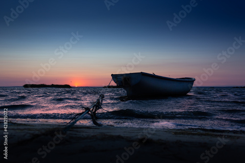 Sunset, sunrise on a wavy sea with boat