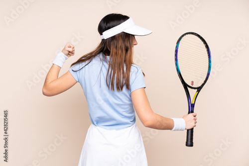 Young caucasian woman isolated on beige background playing tennis and celebrating a victory
