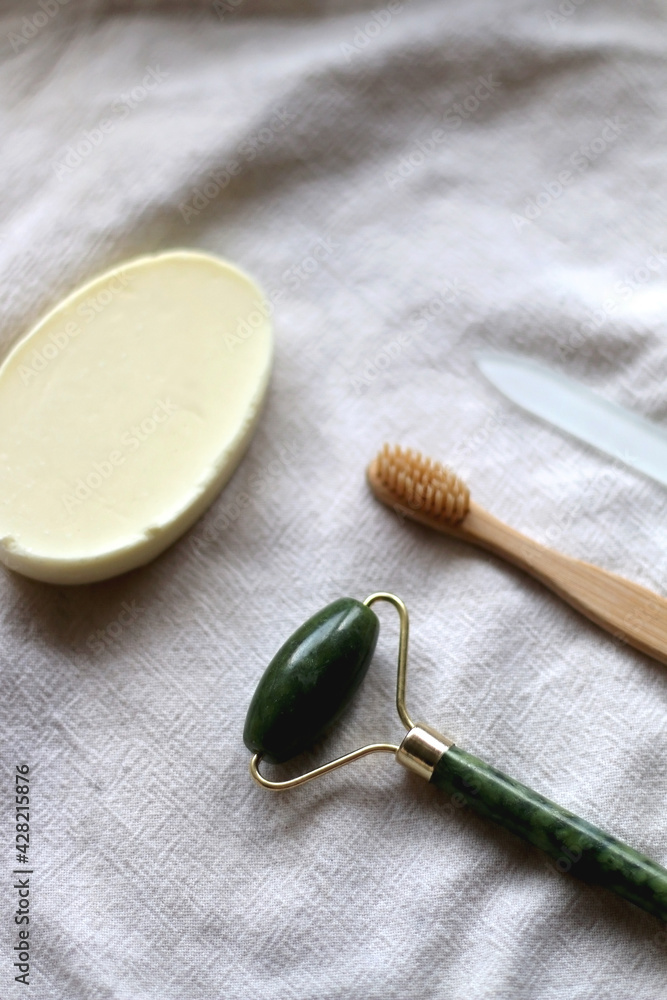 Jade face roller, wooden toothbrush, glass nail file and bar of soap. Sustainable body care products. Selective focus. Jade face roller, wooden toothbrush, glass nail file and bar of soap. Sustainable body care products. Selective focus.
