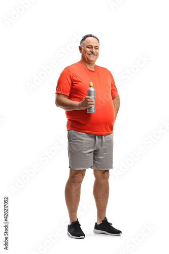 Full length portrait of a corpulent man in sports clothing holding a bottle