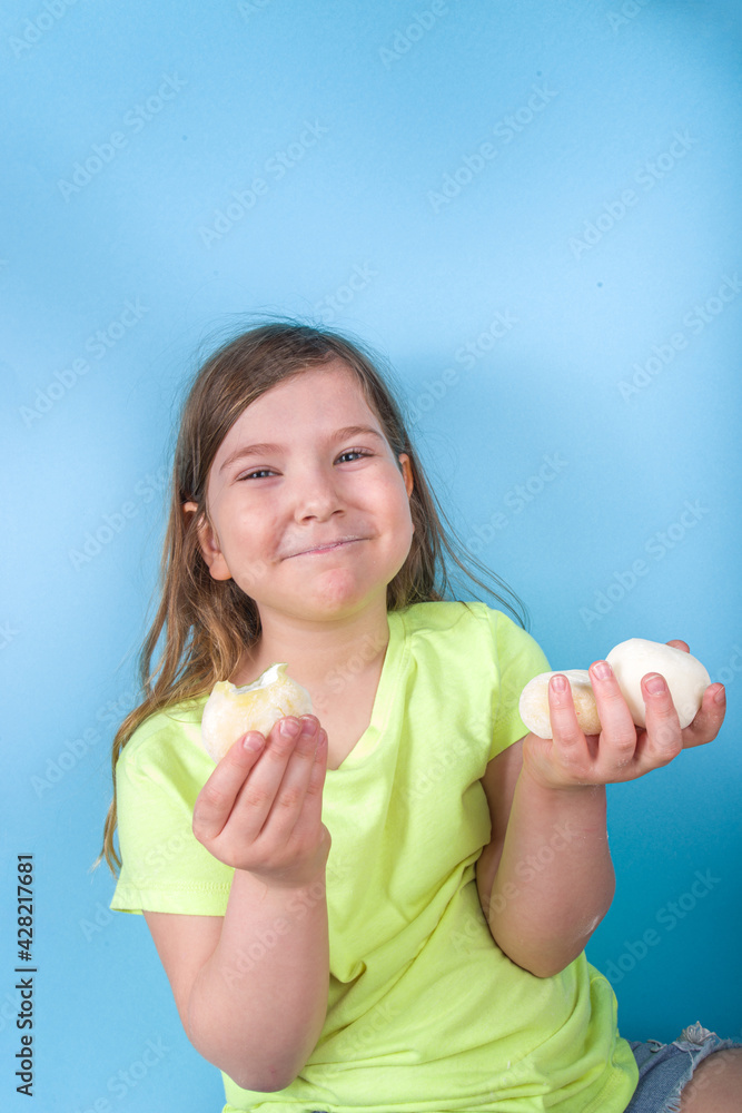Cute preschooler kid enjoy Japanese sweet mochi. Girl child eating trending mochi ice cream with fruit flavors, on a bright blue background Cute preschooler kid enjoy Japanese sweet mochi. Girl child eating trending mochi ice cream with fruit flavors, on a bright blue background