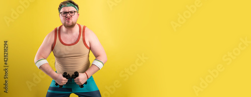 funny fat man doing exercises with dumbbells. Overweight. yellow background