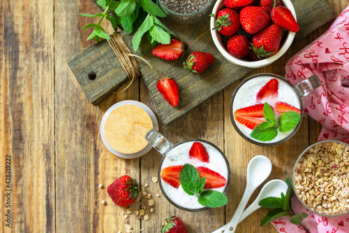 Fototapeta Naklejka Na Ścianę i Meble -  Healthy eating. Breakfast concept. Homemade granola with strawberry, yogurt, chia seeds and fresh berries on a rustic table. Top view flat lay. Copy space.