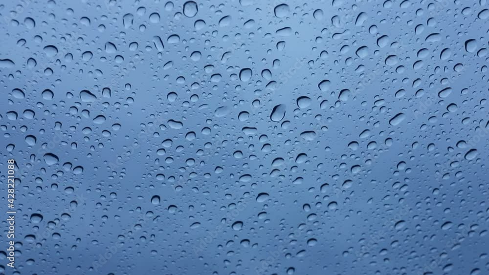 Wet windshield, taken from inside the car.Rain falls on the surface of a car glass window with a gray background. Natural patterns of raindrops on the windshield. Water drops wallpaper. Wet windshield, taken from inside the car.Rain falls on the surface of a car glass window with a gray background. Natural patterns of raindrops on the windshield. Water drops wallpaper.