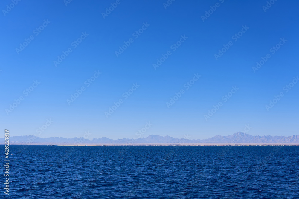 Dreamy seascape with mountain views against blue sky Dreamy seascape with mountain views against blue sky