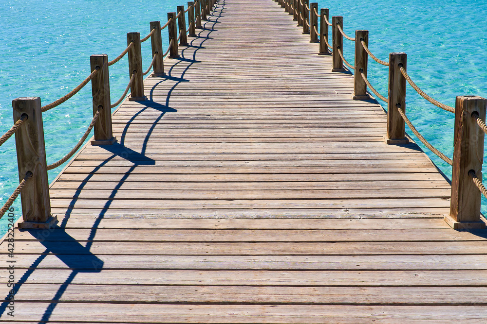 Fototapeta premium Cozy neat wooden bridge against the backdrop of beautiful sea water
