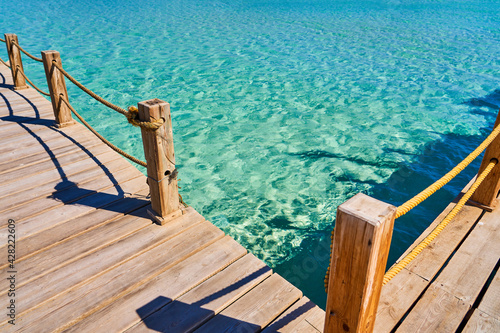 Wooden sea pier with yellow ropes and beautiful clear water