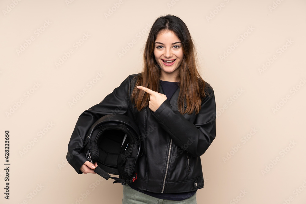 Woman with a motorcycle helmet isolated on beige background surprised and pointing finger to the side Woman with a motorcycle helmet isolated on beige background surprised and pointing finger to the side