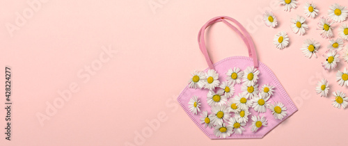 Creative flat lay with daisy flowers and pink fpp2 or KN95 mask