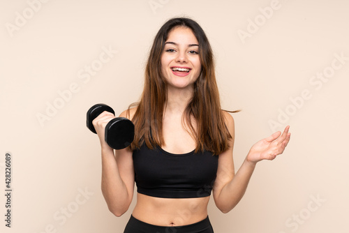 Young sport woman making weightlifting isolated on beige background laughing