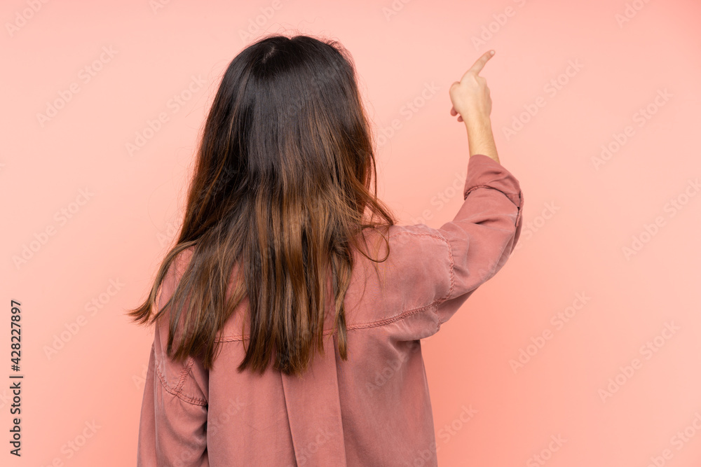 Young caucasian woman isolated on pink background pointing back with the index finger Young caucasian woman isolated on pink background pointing back with the index finger