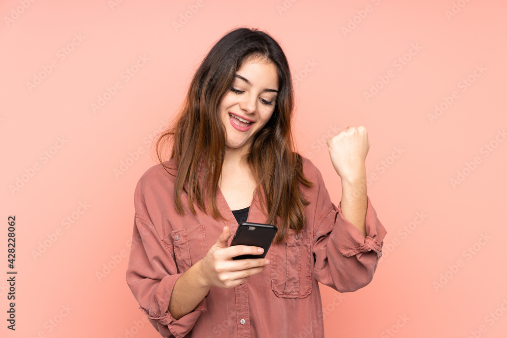 Young caucasian woman isolated on pink background with phone in victory position Young caucasian woman isolated on pink background with phone in victory position