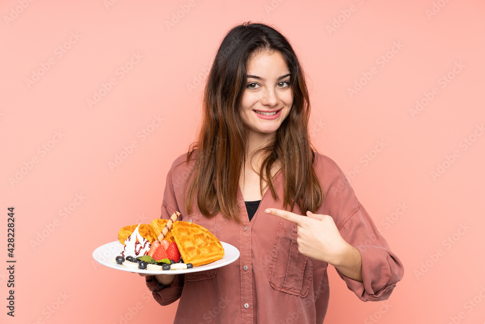 Young caucasian woman holding waffles isolated on pink background with surprise facial expression Young caucasian woman holding waffles isolated on pink background with surprise facial expression