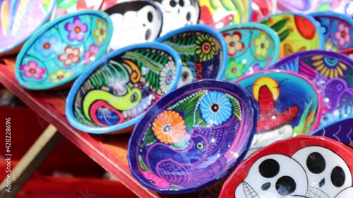 Mexican Colorful Art craft on a street market table. Touristic souvenirs market. Daylight, bright and happy atmosphere. Colorful ceramic with Mexican motives. photo