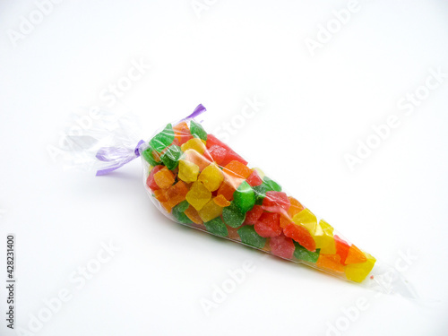Colorful (red, orange, yellow and green) candied fruits in a transparent bag on a white background