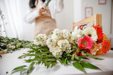 the florist's table is littered with fresh flowers before starting work. Florist in the background
