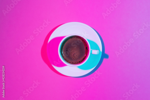 Cup of coffee on pink background. Double colorful shadows