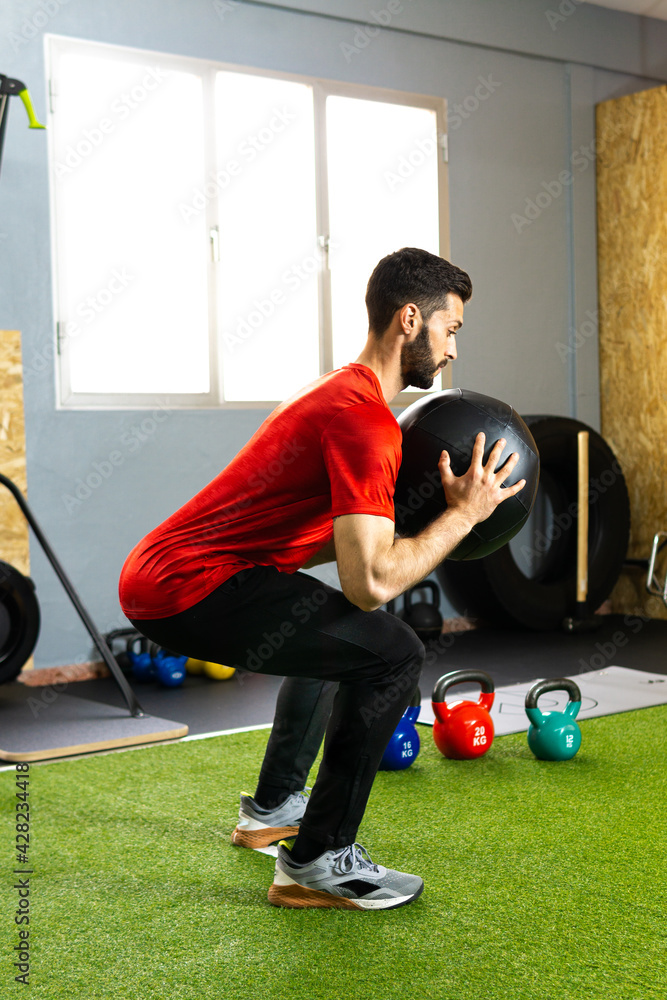Obraz premium Young athlete exercising in the gym with a ball