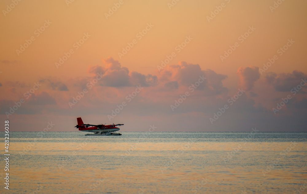 landing of a red seaplane on the maldivian lagoon at sunset. luxurious travel concept