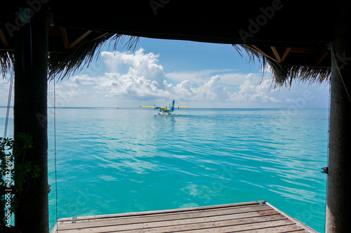 Yellow and blue seaplane on the turquoise maldivian lagoon. pier in the frontground photo