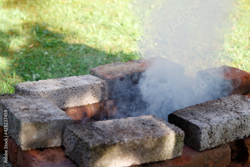 Resting outdoors. Self-made brick grill set up in the garden with smoke coming out of it.