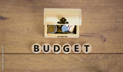 Budget symbol. Concept word budget on wooden cubes on a beautiful wooden background, small wooden chest with coins. Business and budget concept.