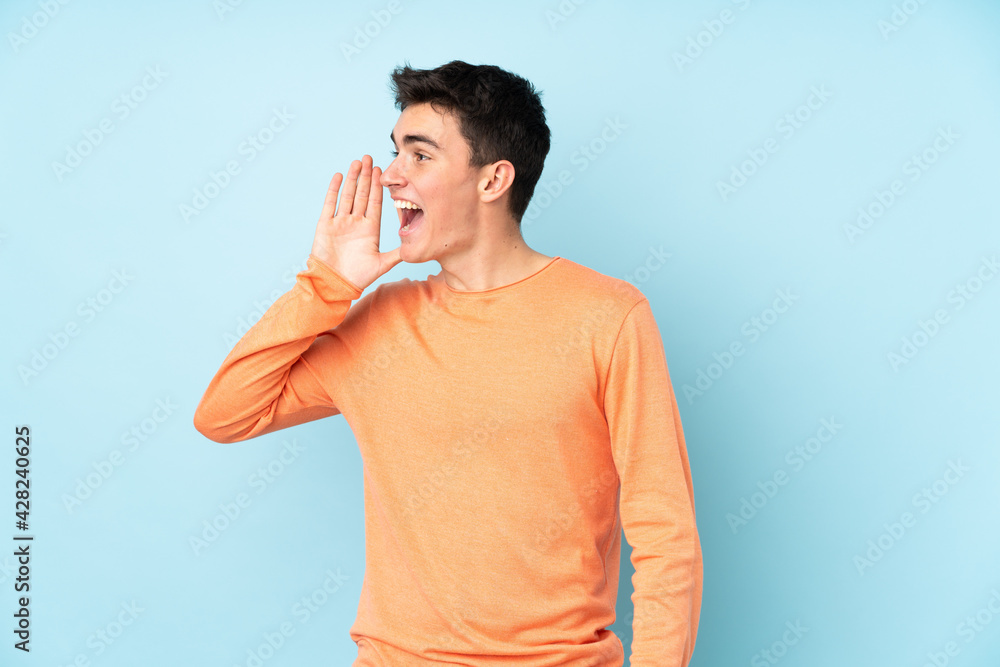 Teenager caucasian handsome man isolated on purple background shouting with mouth wide open Teenager caucasian handsome man isolated on purple background shouting with mouth wide open