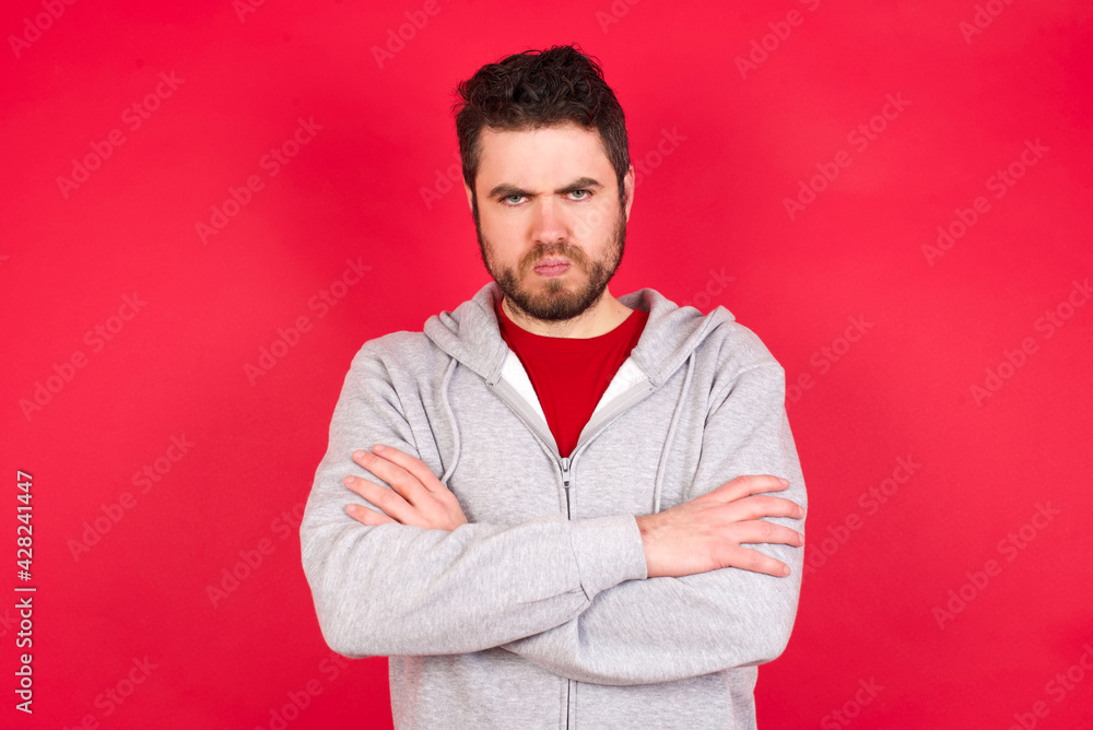 Young caucasian man wearing tracksuit over red background silence gesture keeps index finger to lips makes hush sign. Asks not to share secret Young caucasian man wearing tracksuit over red background silence gesture keeps index finger to lips makes hush sign. Asks not to share secret