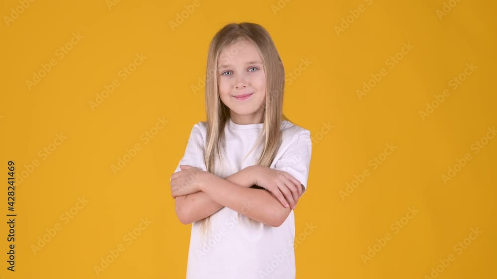 Funny little blonde girl in a white T-shirt smiles and poses on a yellow studio background. People childhood lifestyle concept Funny little blonde girl in a white T-shirt smiles and poses on a yellow studio background. People childhood lifestyle concept
