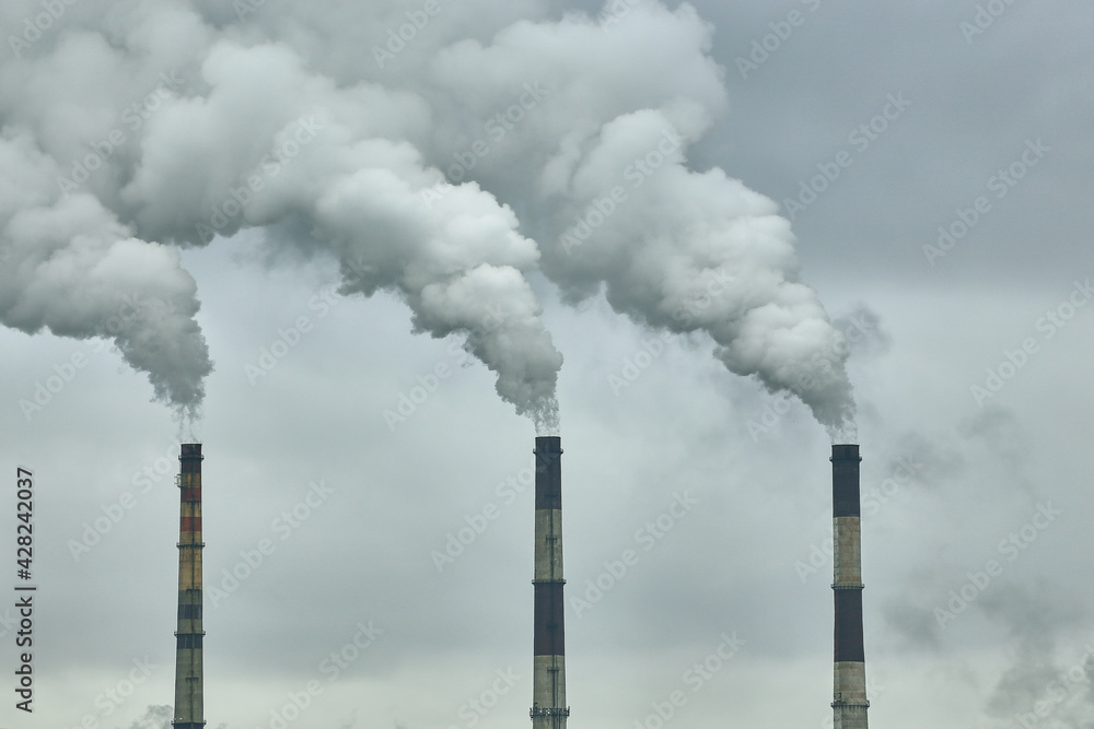 Three chimneys of a thermal power plant on the background of a cloudy sky Three chimneys of a thermal power plant on the background of a cloudy sky