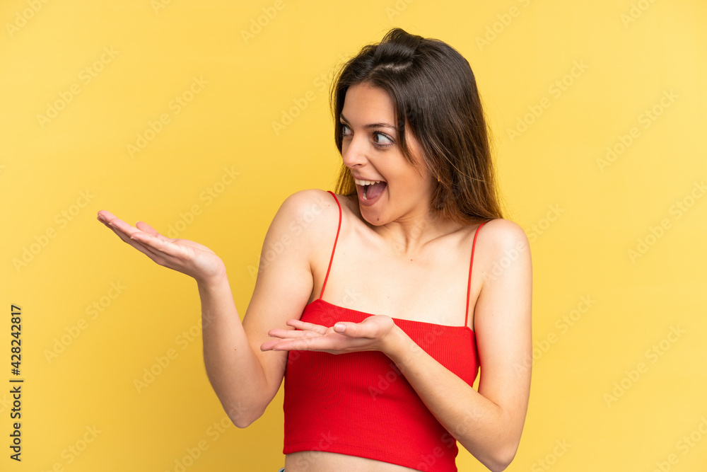Young caucasian woman isolated on yellow background with surprise expression while looking side Young caucasian woman isolated on yellow background with surprise expression while looking side
