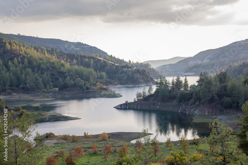 Beautiful landscape with mountains and lake. Turquoise water and beautiful autumn trees with yellow leaves and coniferous forests. Cyprus