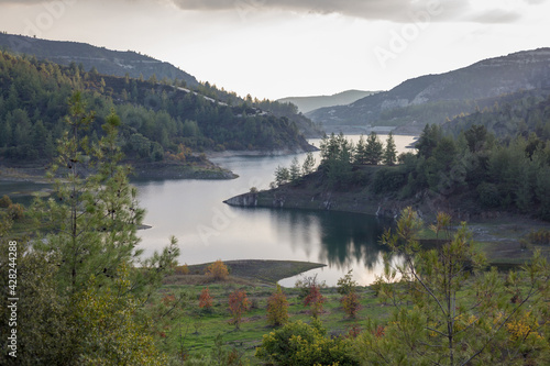 Beautiful landscape with mountains and lake. Turquoise water and beautiful autumn trees with yellow leaves and coniferous forests. Cyprus