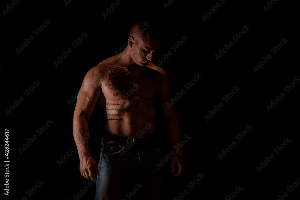 Man posing and showing his arm muscles while posing on black background
