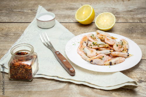 Fresh cooked shrimp, prawns on white plate with lemon, salt and spices. Delicious healthy seafood, protein meal