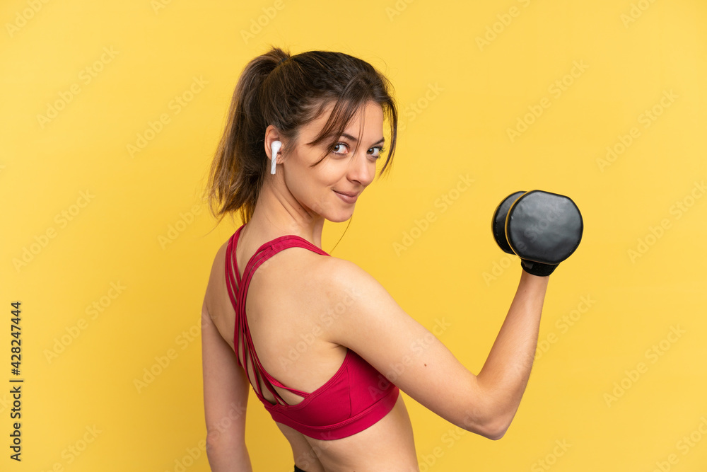 Young caucasian woman isolated on blue background making weightlifting