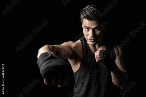 Portrait of young sportsman in boxing wraps posing in boxing stance © a_medvedkov