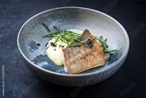 Modern style traditional fried skrei cod fish filet with mashed potatoes and glasswort served as close-up on ceramic design bowl with copy space