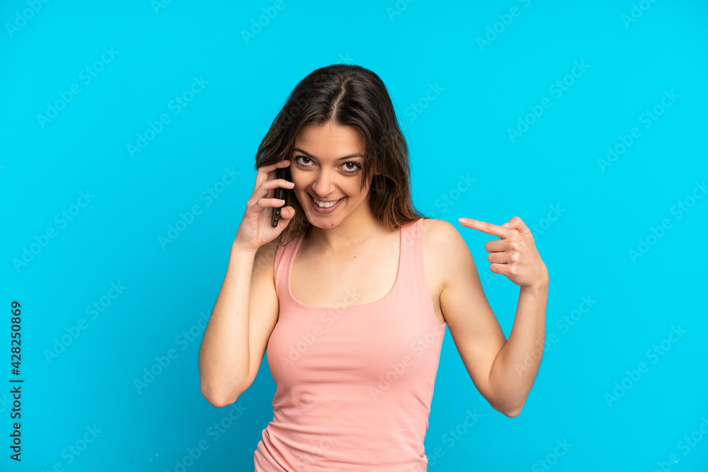Young caucasian woman using mobile phone isolated on blue background giving a thumbs up gesture Young caucasian woman using mobile phone isolated on blue background giving a thumbs up gesture