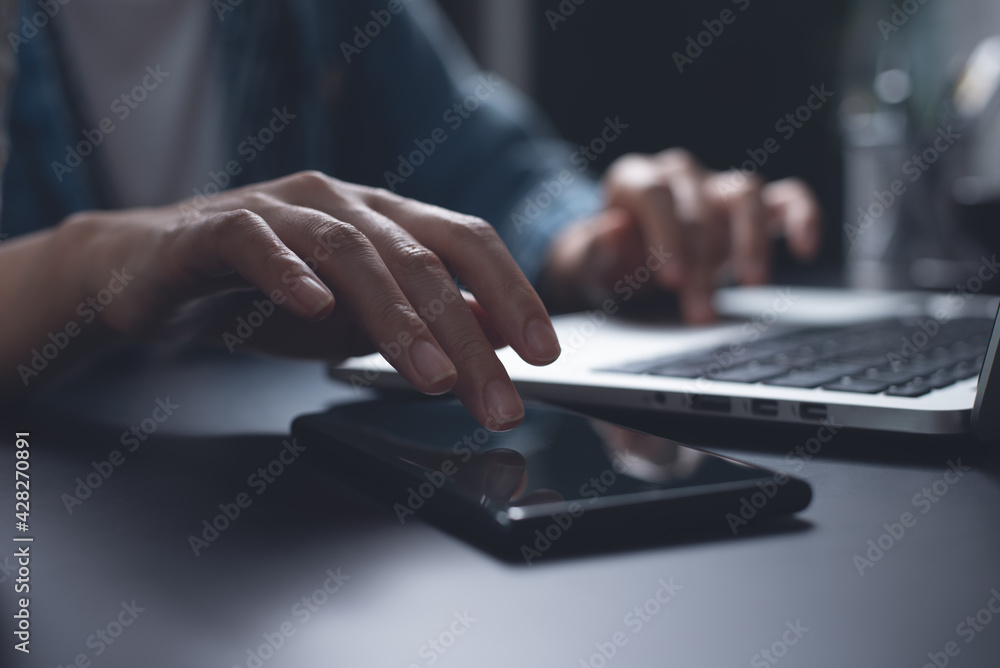 Business woman overtime working on laptop computer and using mobile phone at night from home office Business woman overtime working on laptop computer and using mobile phone at night from home office