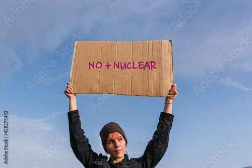 Young activist woman holding a poster against nuclear power and sewage dumping. there is no planet B.