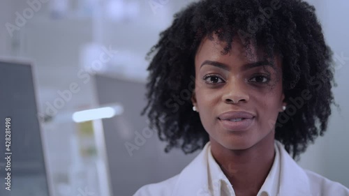 African female doctor in laboratory. Satisfied with her work. Looking at camera with smile. Close up on face