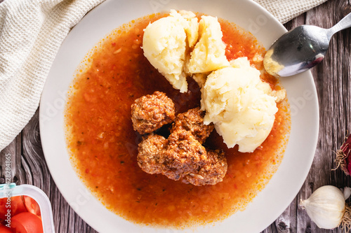 Top view on meat balls in a plate with tomato sauce and mashed potatoes on wooden rustic table - homemade food healthy eating traditional meal copy space