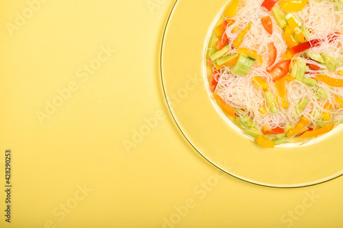 Closeup shot of funchoza salad with bell peppers isolated on a yellow surface photo